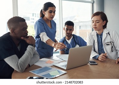 Putting In The Long Hours. Shot A Group Of Doctors Discussing Work Matters In The Office At Work.