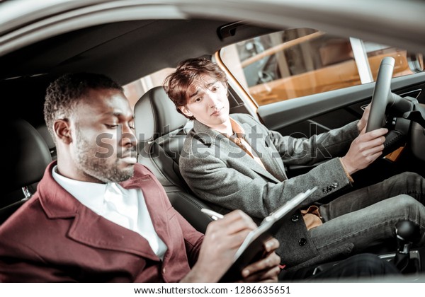 Putting marks. Professional driving\
instructor putting marks after driving to young\
student