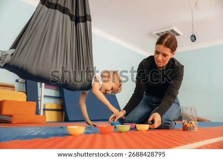Putting the objects into bowls while hanging. Preschool child with teacher during developmental activities in a playroom.