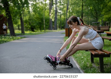 Putting on rollers in the park while sitting on a bench.