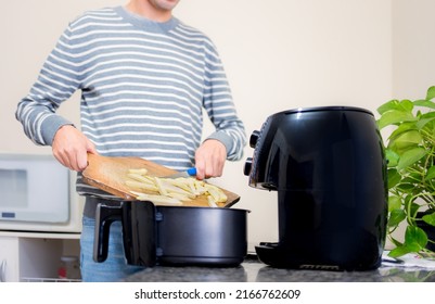 Putting sliced and frozen potatoes in the Airfryer for frying. Making healthy food without frying using oil. - Shutterstock ID 2166762609