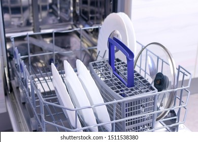 Putting White Utensil And Cutlery In Basket Of Dishwasher And Loading To Wash Dishes Close It. Cleaning In Kitchen, Chores. Household Duties Using Appliances In Kitchen.