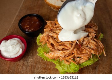 Putting Yogurt Sauce On Shredded Chicken Sandwich