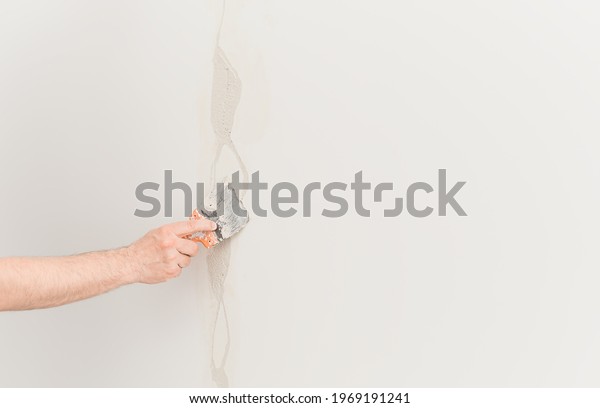 Putty\
knife with putty in hand, worker puts plaster on the wall.\
Selective focus. The concept of renovation work in apartments or\
offices, construction. Free space for ad or\
text