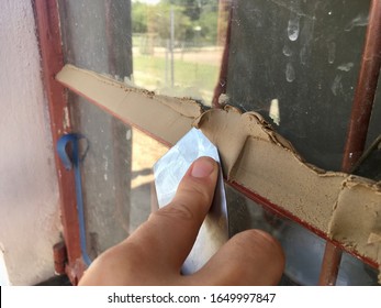 Puttying Or Applying Putty To Hold A Glass Pane On To The Window Frame .