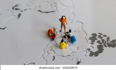 Miniature tourists on world map puzzle.