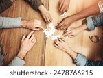 Puzzle, above and hands of business people for teamwork, collaboration and working together. Meeting, diversity and workers with jigsaw for problem solving, challenge and cooperation in office