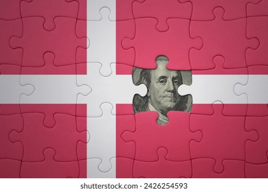 puzzle with the colourful national flag of denmark and usa dollar banknote. finance concept