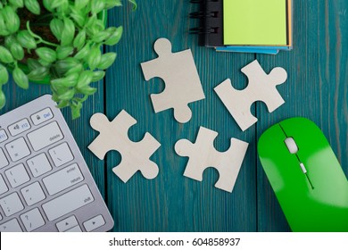 Puzzle pieces, sketchbook, computer keyboard and mouse on a blue wooden background