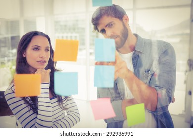 Puzzled Business Team Looking Post Its On The Wall In The Office