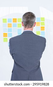 Puzzled Businessman Looking Post Its On The Wall In The Office