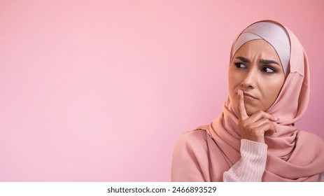 Puzzled face. Decision doubt. Smart contemplation. Portrait of pensive perplexed curious woman in hijab isolated on pink empty space advertising background. - Powered by Shutterstock