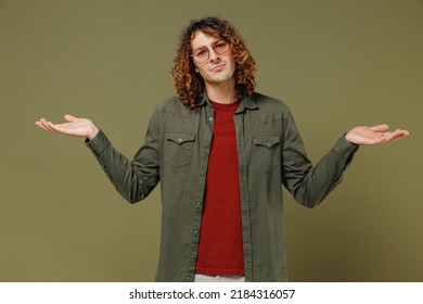 Puzzled Long Curly Hair Young Brunet Man 20s Wears Khaki Shirt Spreading Hands Shrugging Shoulders Have No Idea Standing Questioned And Unaware Isolated On Plain Olive Green Background Studio Portrait