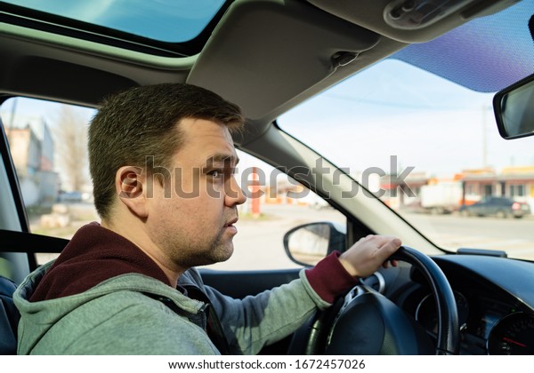 puzzled man in the grey sweater behind the wheel\
of the car rides and looks\
forward