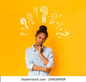 Puzzled Pensive Young African American Teen Girl In Casual T-shirt Posing Over Orange Background With White Question Marks