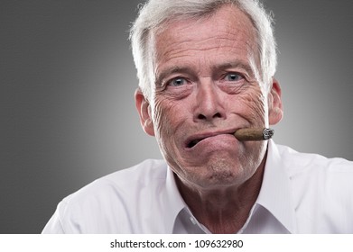 Puzzled senior man on gray background. Studio shot of puzzled senior man with cigar in his mouth