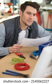 Puzzled Technician Reading Wiring Instructions