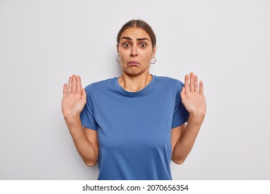 Puzzled woman with dark hair raises palms looks perplexed says I am not guilty not gonna hep looks in dismay wears casual blue t shirt isolated over white background. Human reaction concept. - Shutterstock ID 2070656354