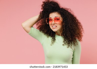 Puzzled Young Curly Latin Woman 20s Years Old Wears Mint T-shirt Sunglasses Scratching Head Standing Questioned And Unaware Have No Idea Isolated On Plain Pastel Light Pink Background Studio Portrait