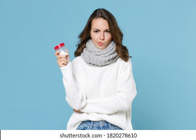 Puzzled Young Woman In White Sweater Scarf Hold Medication Tablets, Aspirin Pills In Bottle Isolated On Blue Background Studio Portrait. Healthy Lifestyle Sick Disease Treatment Cold Season Concept