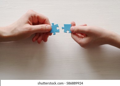 Puzzles. Hand of the child and hand of mother fold puzzle, closeup, top view - Shutterstock ID 586889924