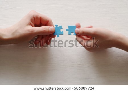 Puzzles. Hand of the child and hand of mother fold puzzle, closeup, top view