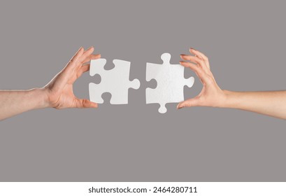 Puzzles. Man and woman holds in hand a jigsaw puzzle. Business solutions, success and strategy concept. Hands connecting puzzle. Hand of the man and hand of woman fold puzzle, closeup. - Powered by Shutterstock