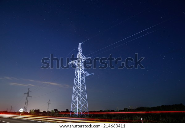 Pylon for electricity distribution at night with\
car lights in front