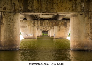 Pylons Or Concrete Pillar Of The Bridge In The Water Of The River, Facing Each Other In A Staggered Downward Recessive Manner As A Portal To Another Location Or Place. Photo Under The Bridge