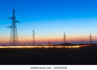 Pylons and electrical power lines at dusk with traffic lights in front - Powered by Shutterstock