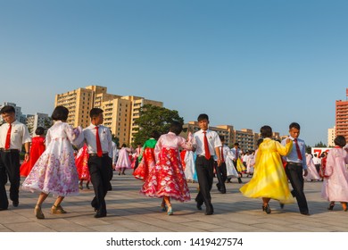 Pyongyang, North Korea - July 27, 2014: Mass Dance In Honor Of Victory Day In The War At The Workers Party Foundation Monument. Korean People In Traditional Dresses Dance In The Street.