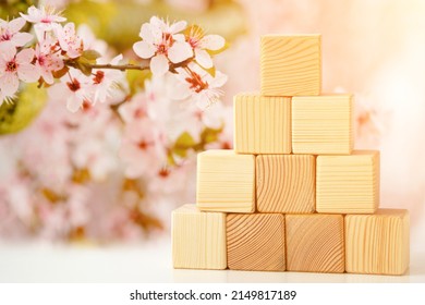 The pyramid is built of wooden cubes against the backdrop of a flowering garden. Banner mockup for design montage, business hierarchy development concept. Concept of business growth to success