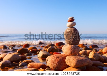 Pyramid of multicolored pebbles on a background of the summer sea. Concept of harmony, balance and meditation