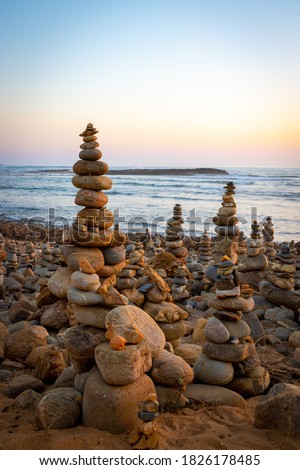 Pyramid of sea pebbles at beach on sunset, life balance and harmony concept