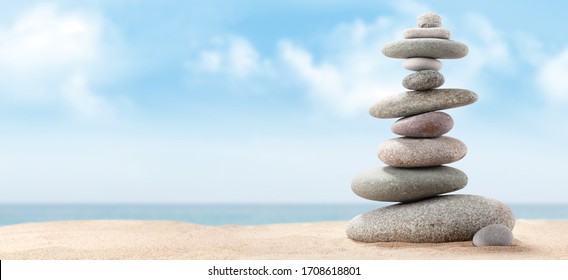 Pyramid of sea pebbles on a sunny sand beach. Life balance and harmony concept