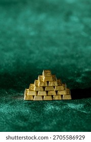 pyramid stack of shiny gold bars placed on green velvet surface symbolizing investment and trading
