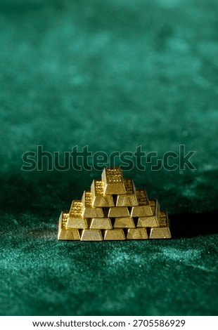 pyramid stack of shiny gold bars placed on green velvet surface symbolizing investment and trading