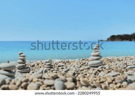 Pyramid stones balance on the beach against the background of the sea and the sky. Object in focus, blurred background, idea of a vacation or retweet by the sea