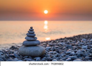 Pyramid of stones for meditation lying on sea coast at sunset