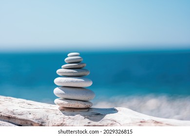 Pyramid stones on the seashore on a sunny day on the blue sea background. Happy holidays. Pebble beach, calm sea, travel destination. Concept of happy vacation on the sea, meditation, spa, calmness. - Shutterstock ID 2029326815
