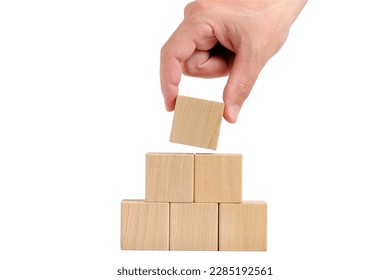 Pyramid of wooden cubes is completed with help hand.Concept of development - Shutterstock ID 2285192561