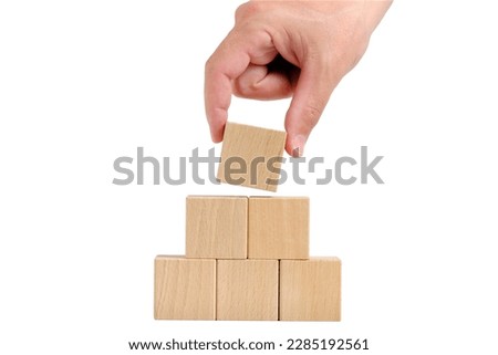 Pyramid of wooden cubes is completed with help hand.Concept of development