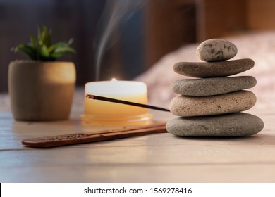 Pyramid Of Zen Stones, Burning Candle, Incense Stick, Bedroom Interior. Evening Meditation Concept. Close Up.