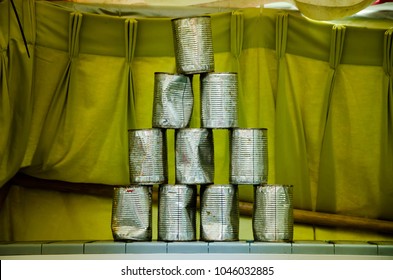 pyramids of tin cans for throwing balls at them on yellow green cloth background
