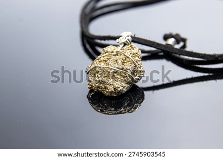 Pyrite stone wrapped in silver wire forms a unique pendant on a black cord necklace. This jewelry piece highlights natural elegance and artisanal craftsmanship for fashion use.