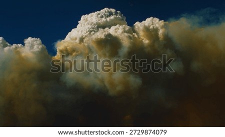 Pyrocumulus clouds fueled by raging wildfires dwarf vulnerable western mountain range. 