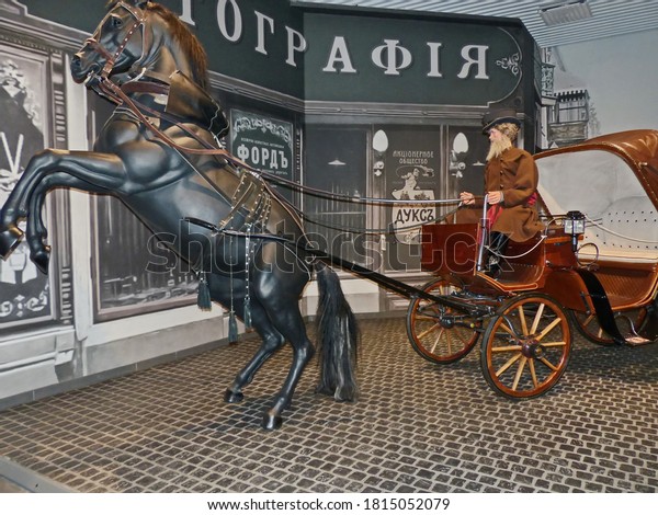Pyshma, Russia - 09/12/2020: Exhibition of\
retro cars. Horse-drawn carriage with coachman. The horse raised on\
its hind legs. Horse-drawn transport is the progenitor of\
automobile transport.