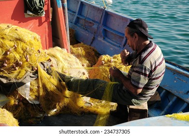 PYTHAGOREIO, GREEK, JUNE 07, 2005 - Fisherman corrects fishing net in harbor 