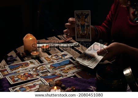 Pythoness reads tarot cards in a dark environment