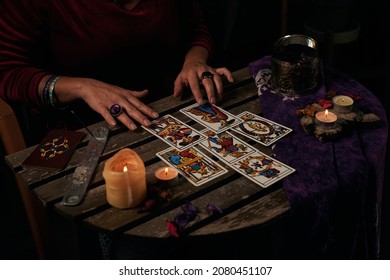 Pythoness reads tarot cards on a table with candles - Shutterstock ID 2080451107